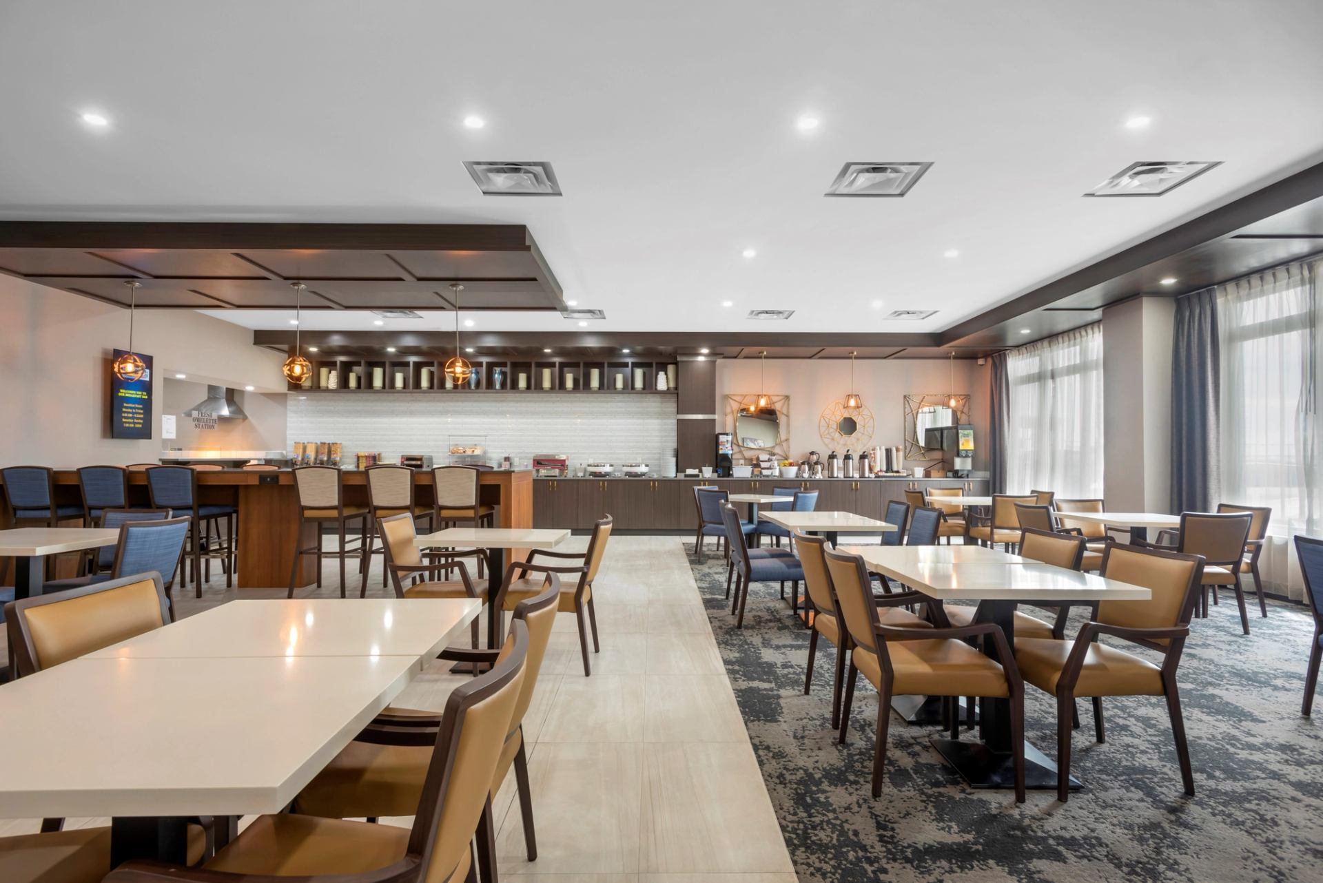 Modern hotel dining area with tables, chairs, and bar seating.