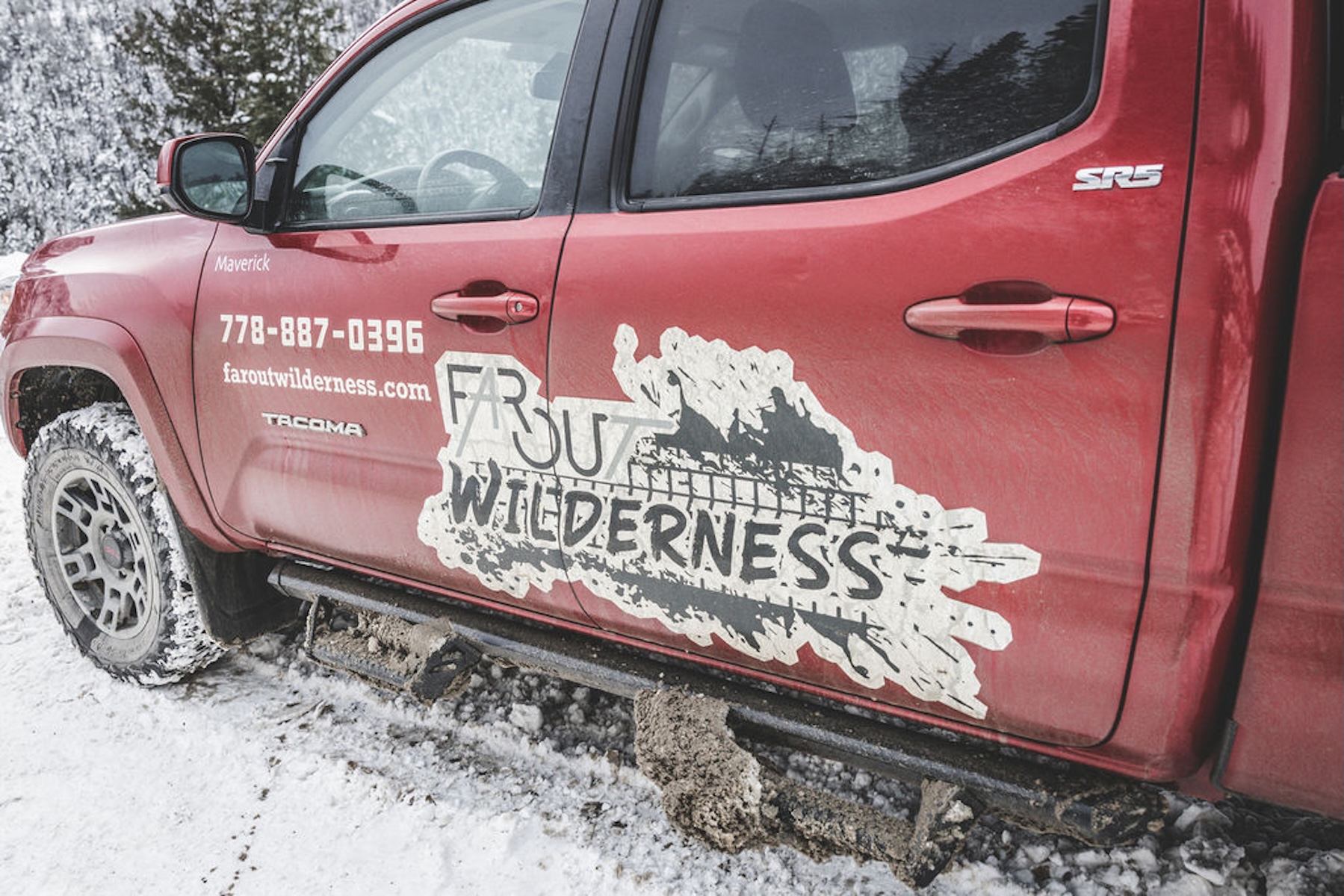 Close‑up of a red 4x4 truck with Winter Explorer branding parked on a snowy road.