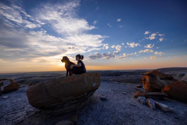 Woman with dog in Red Rock Coulee landscape.