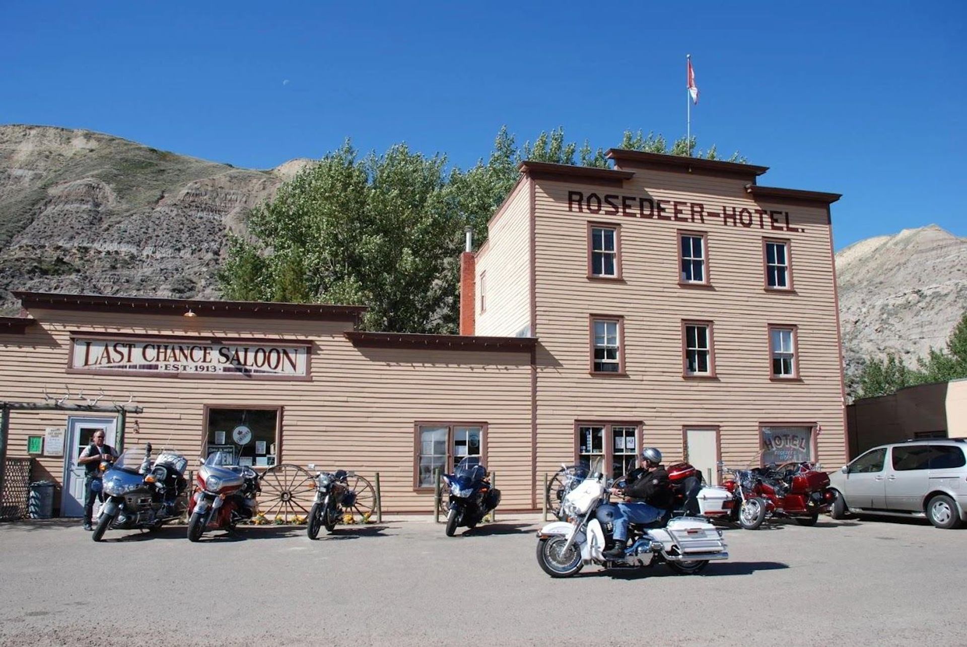 Historic Rose Deer Hotel and Last Chance Saloon with parked motorcycles and hills behind.