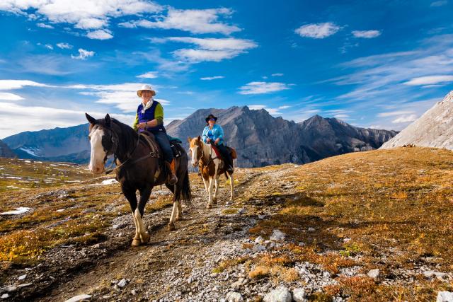 Couple horseback riding on a trail in the mountains in Banff National Park