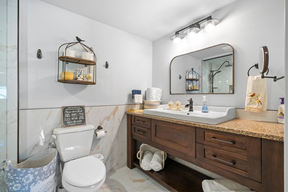 Bathroom with wooden vanity, large mirror, and modern fixtures.