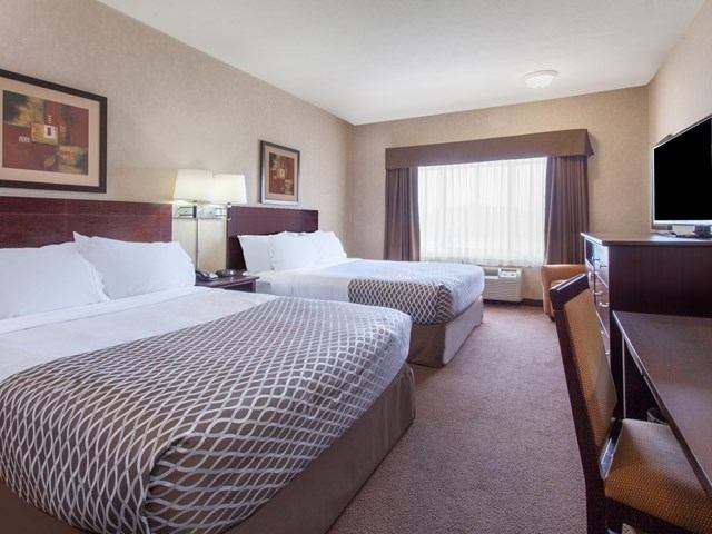 Hotel room with two queen beds, desk, chair, and flat-screen TV.