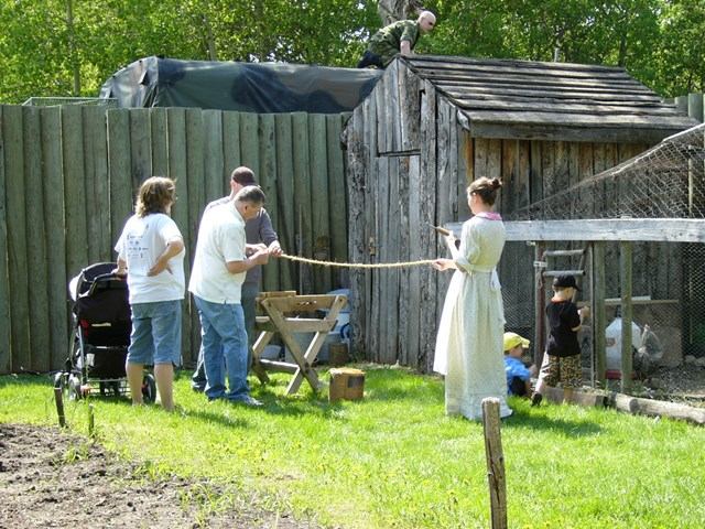 An Interpreter guides a group of guests in making rope in front of the chicken run.