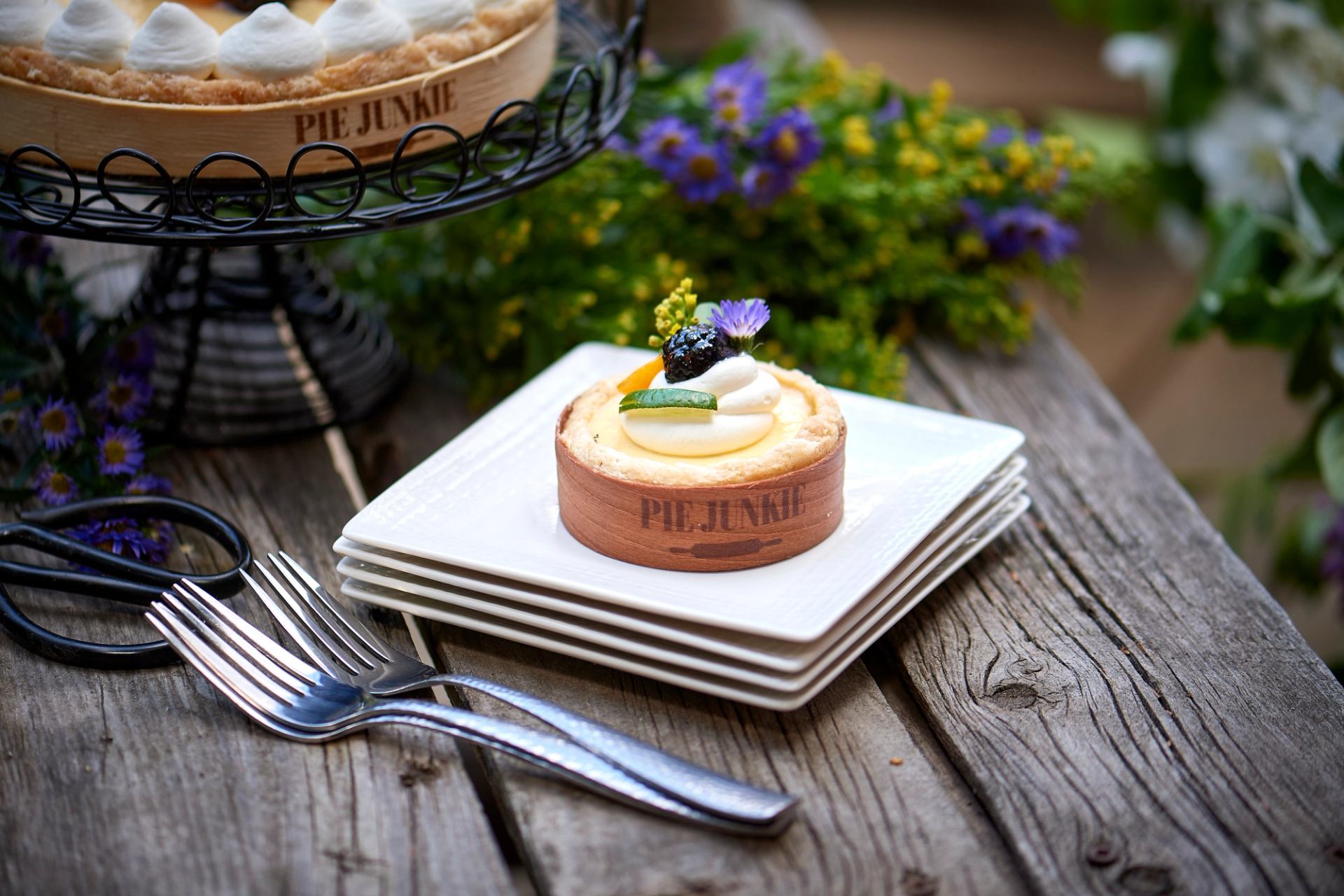 Shows a delicious individual key lime pie topped with edible flowers and whipped cream.