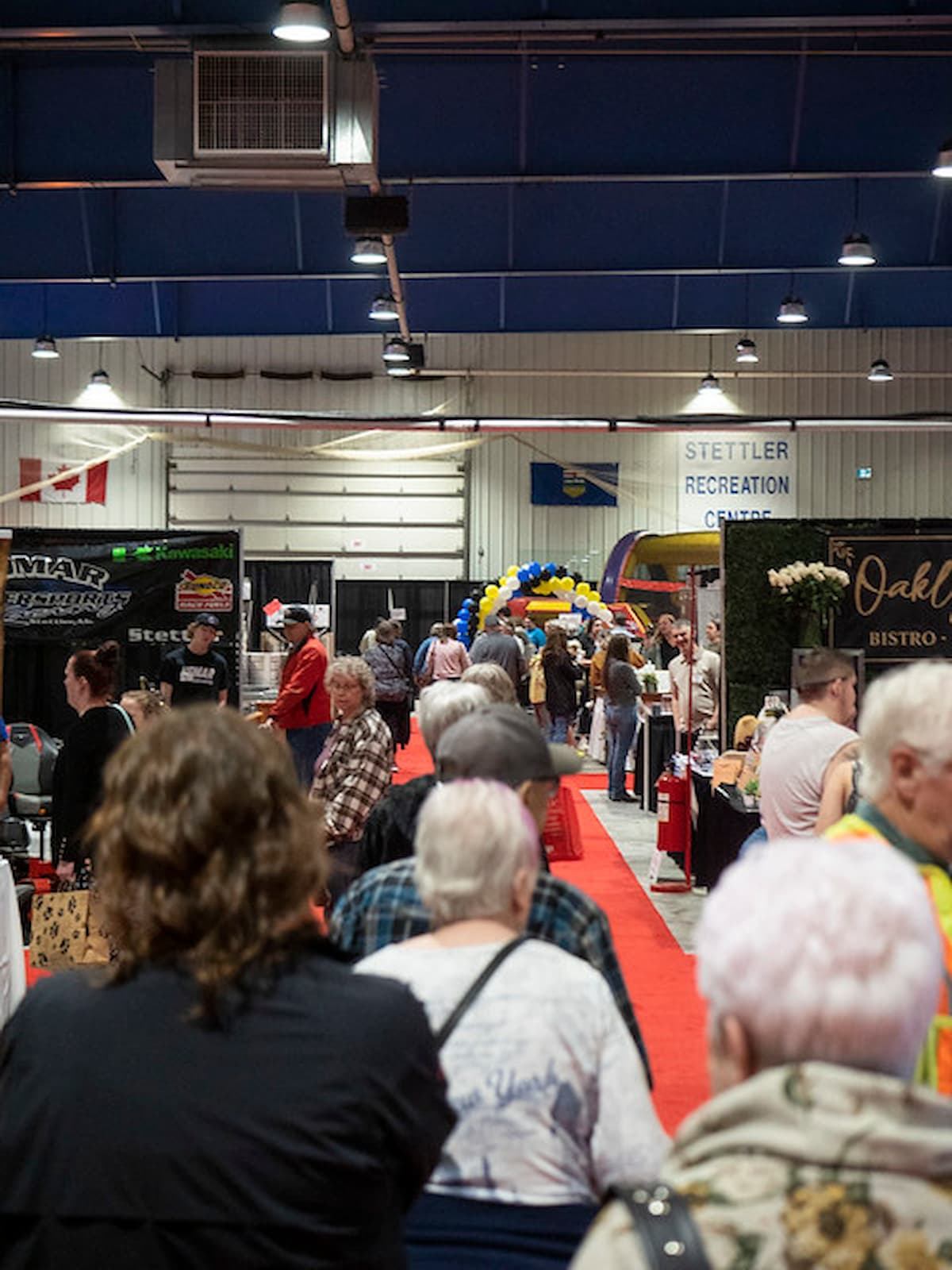 Visitors line up on red carpet at indoor trade show with booths.