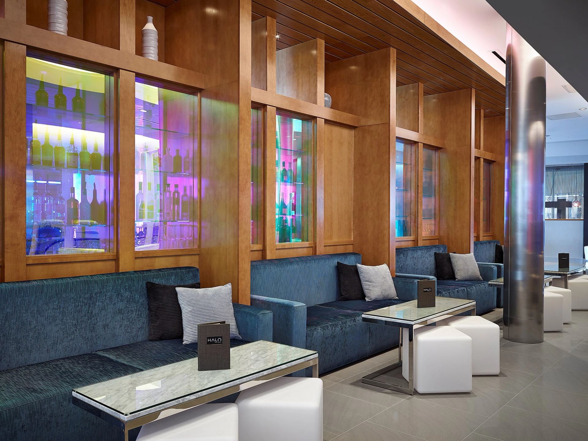 Modern lounge with blue seating, cube stools, and glass-panel dividers at HALO Bar|Bistro.