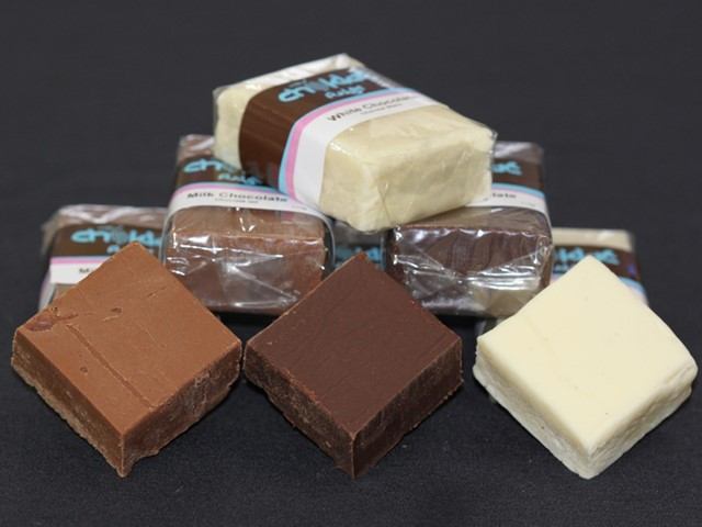 Assorted chocolate bars in white, milk, and dark varieties stacked on a black background.