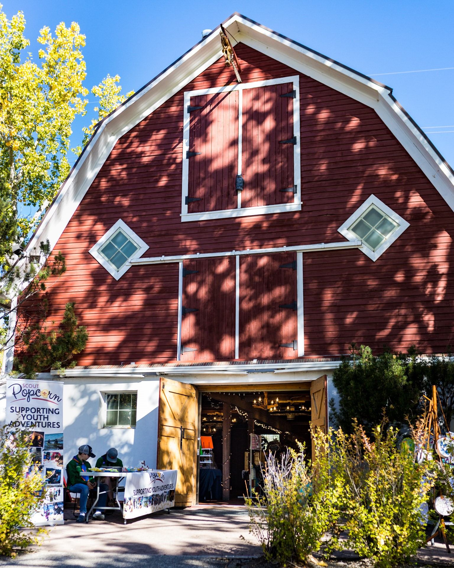 Red barn with open doors, outdoor table, and Scout popcorn fundraising sign.