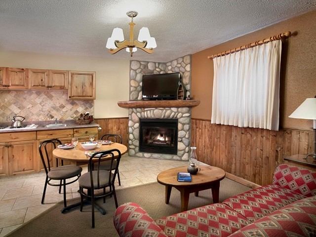 Rustic living room with stone fireplace, wood furniture, and cozy seating.