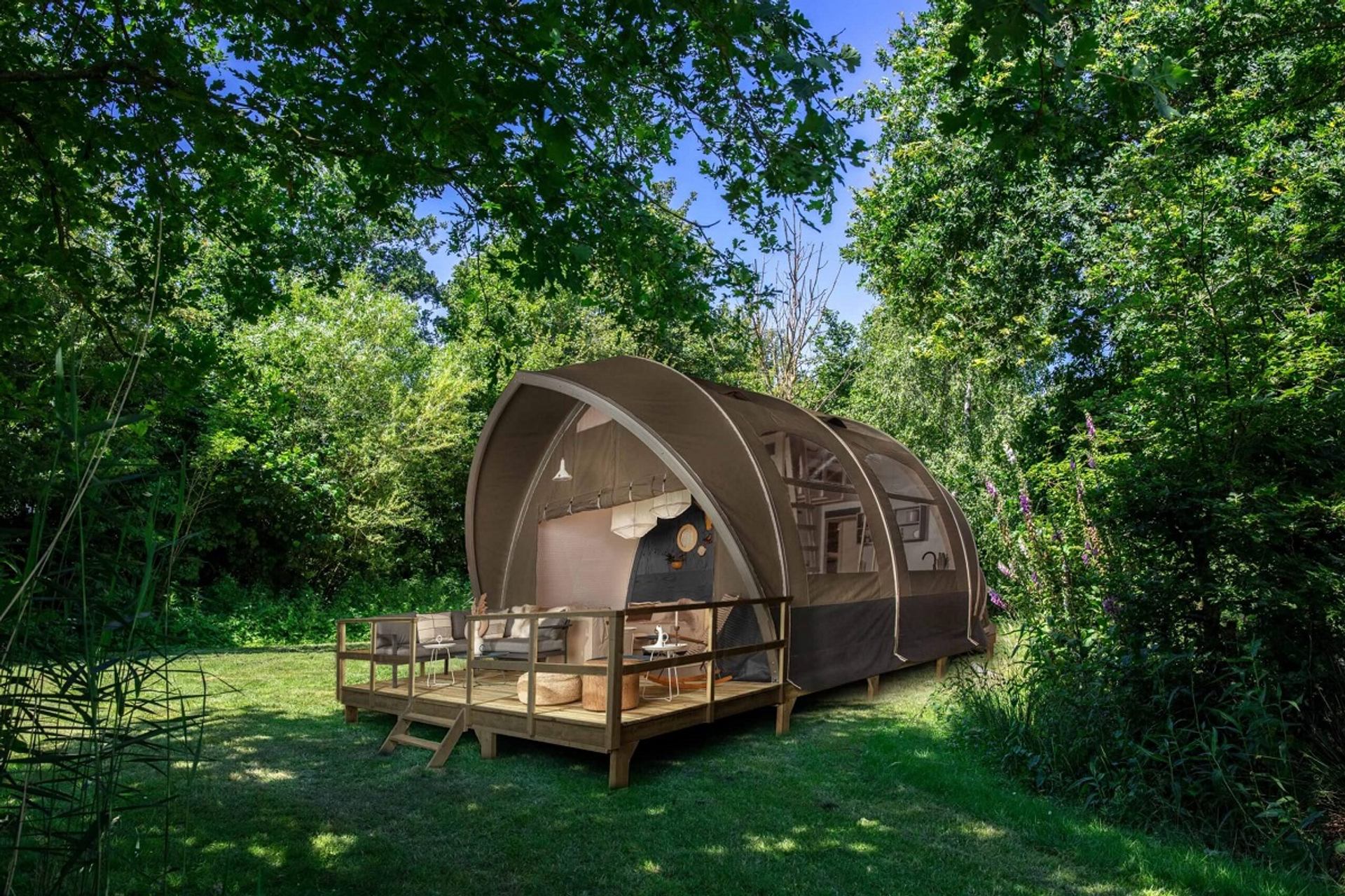 Luxury glamping pod with deck surrounded by lush greenery at Glamping Resorts.