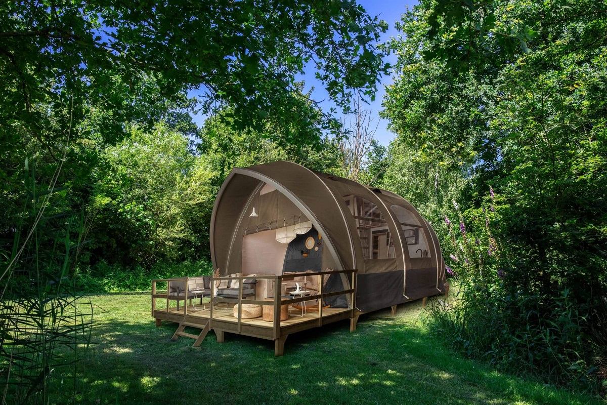 Luxury glamping pod with deck surrounded by lush greenery at Glamping Resorts.