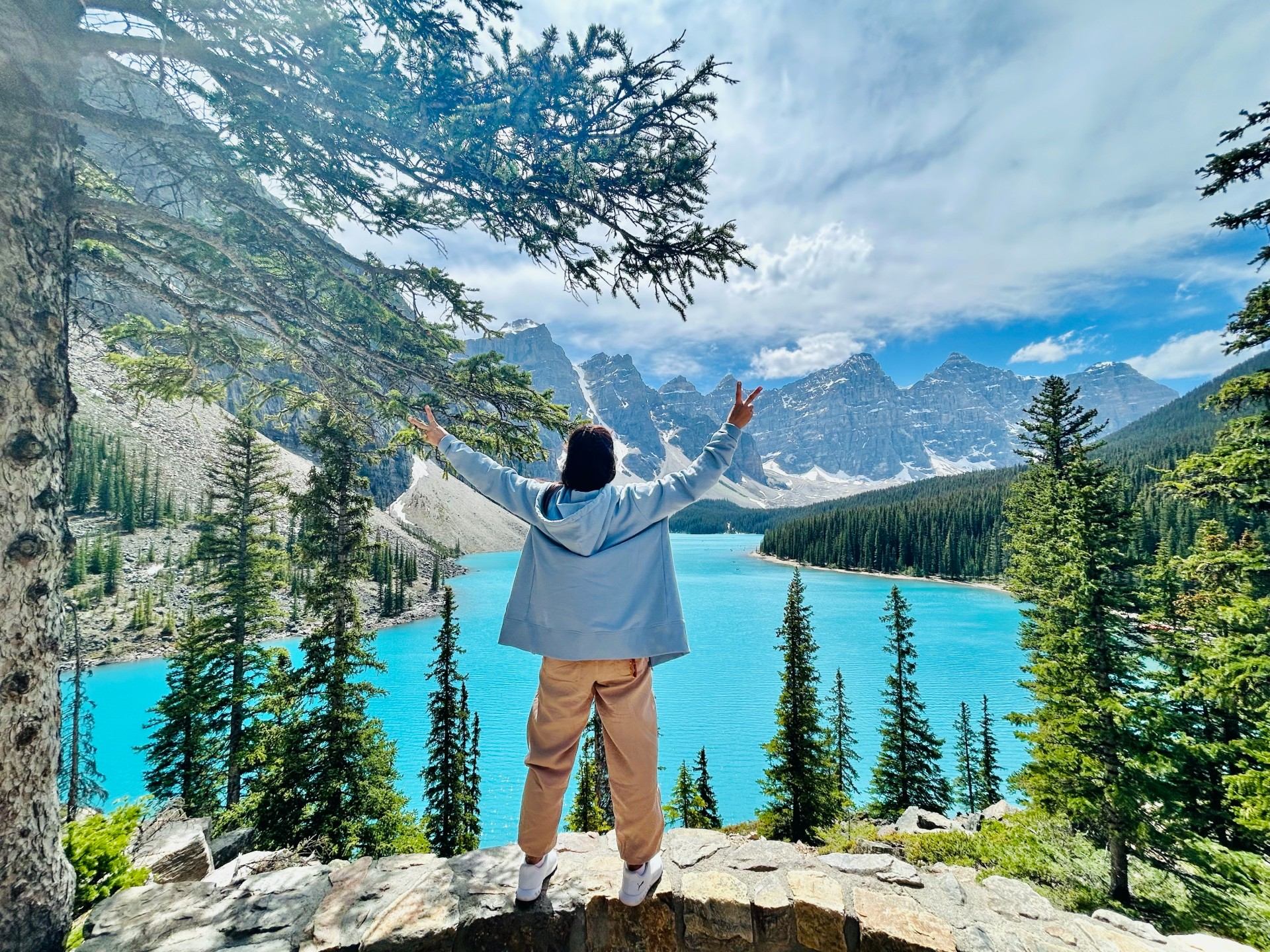 A man stood on a rock with his arms in the air, enjoying the scenery