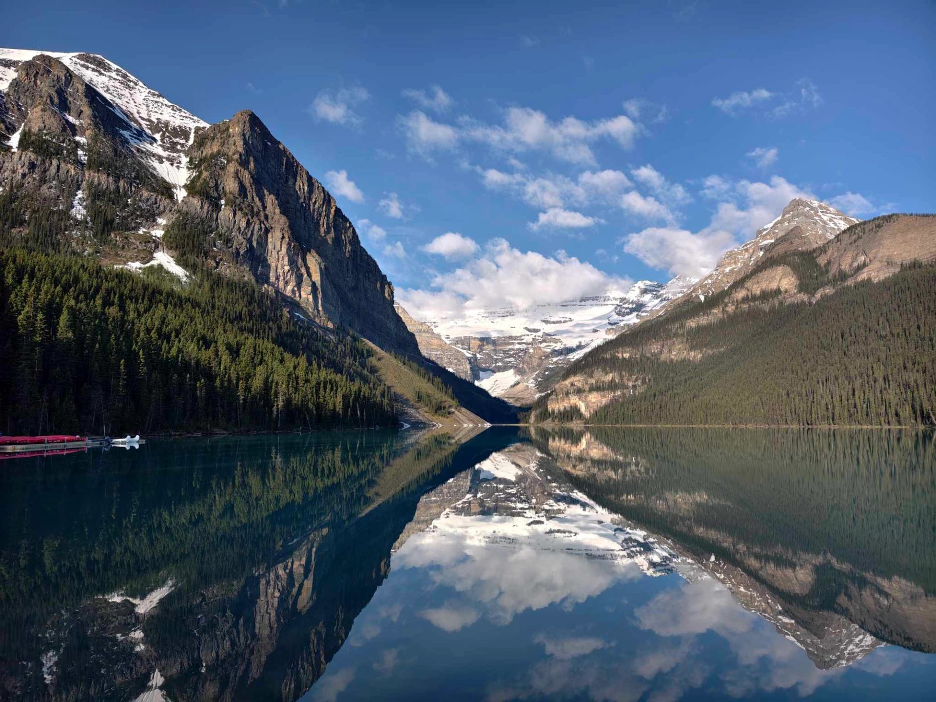 Clear reflections of snowy peaks on the calm waters of Lake Louise.