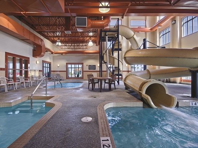 Indoor pool area with waterslide, hot tub, and seating.