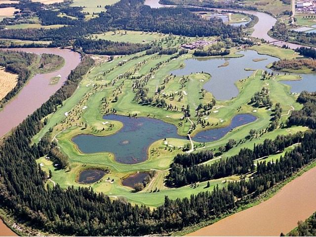 Aerial view of golf course with fairways, bunkers, and river.