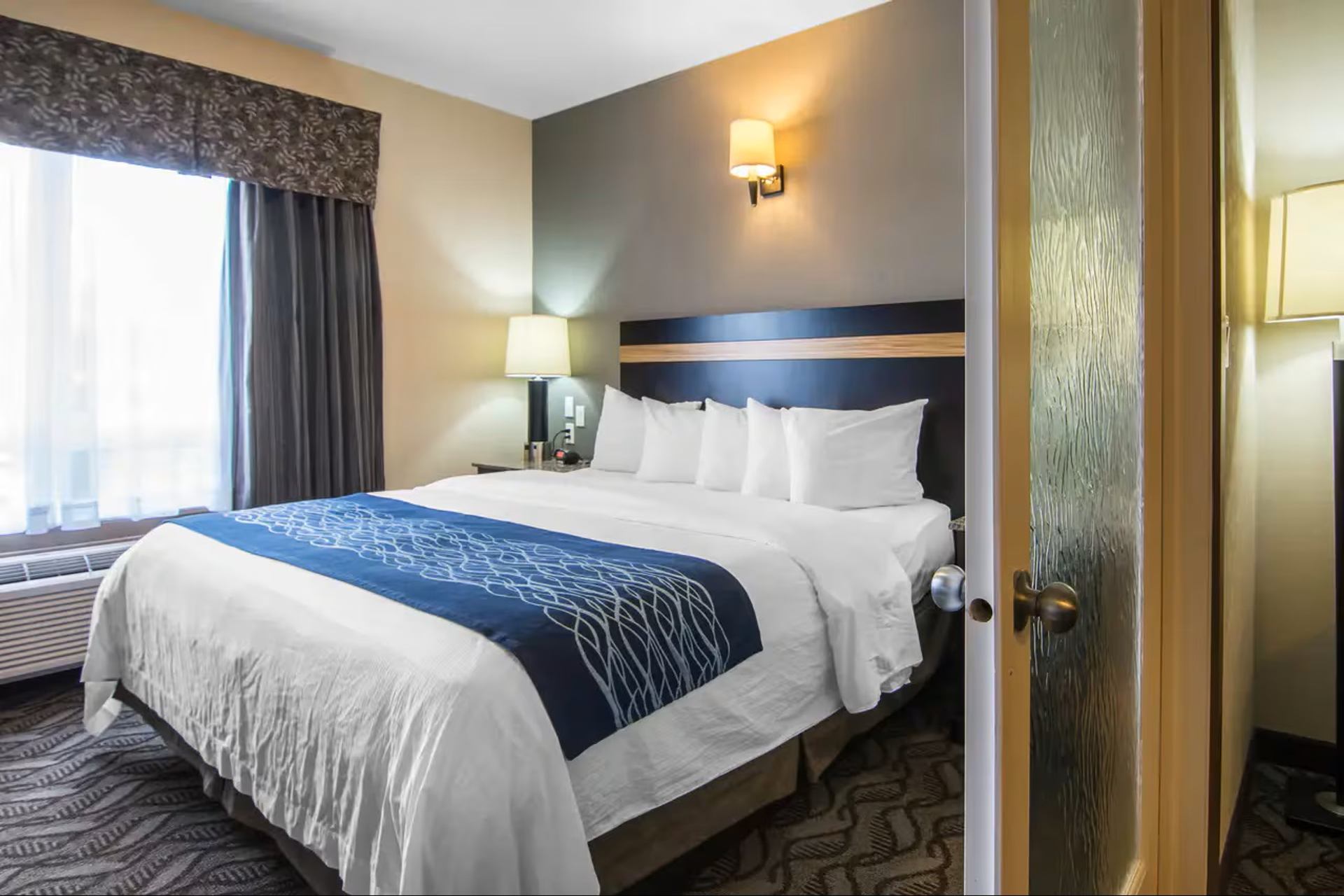 Guest room featuring a king bed, soft lighting, large window, and contemporary furnishings throughout.