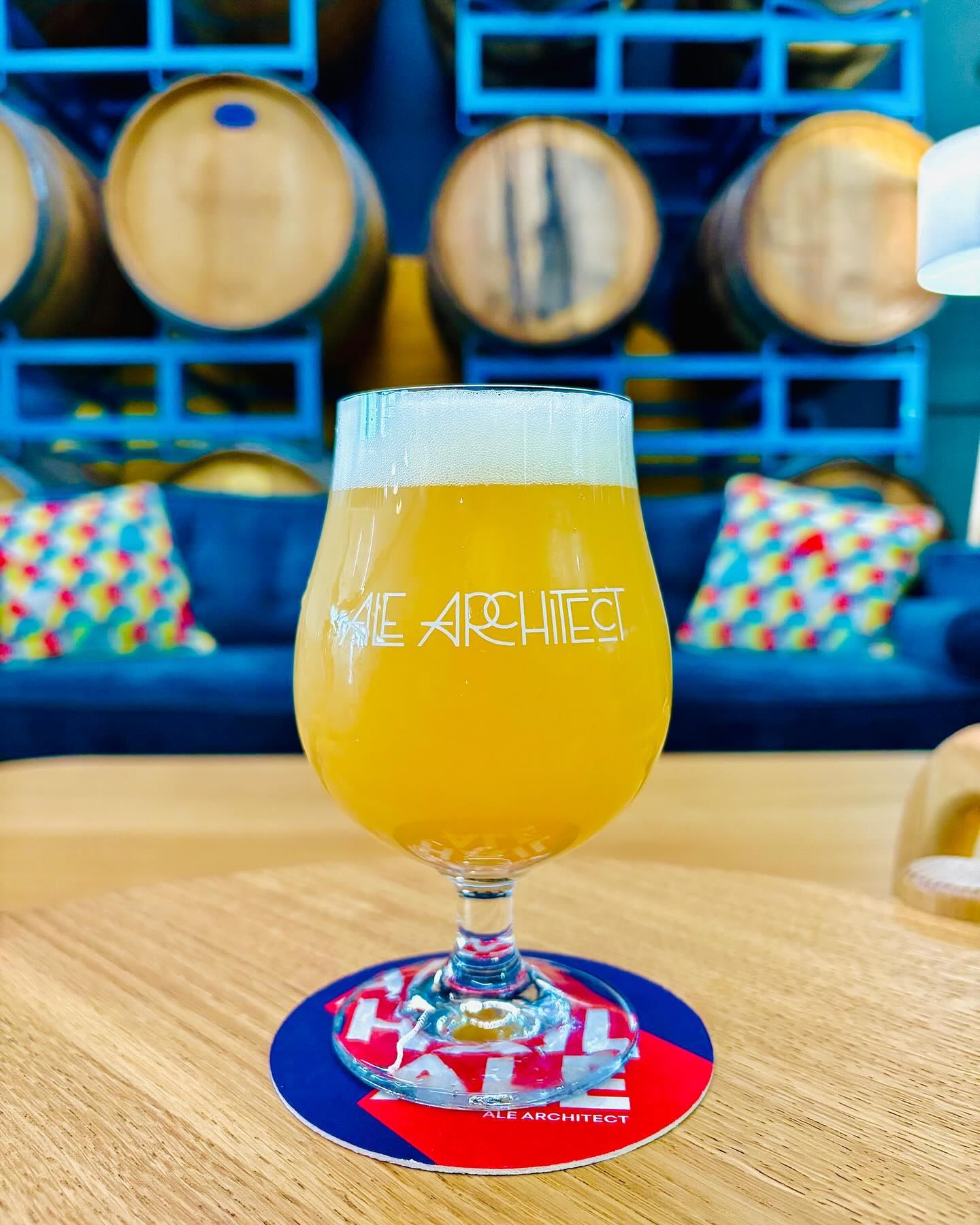 Ale Architect IPA with Barrels in the background.