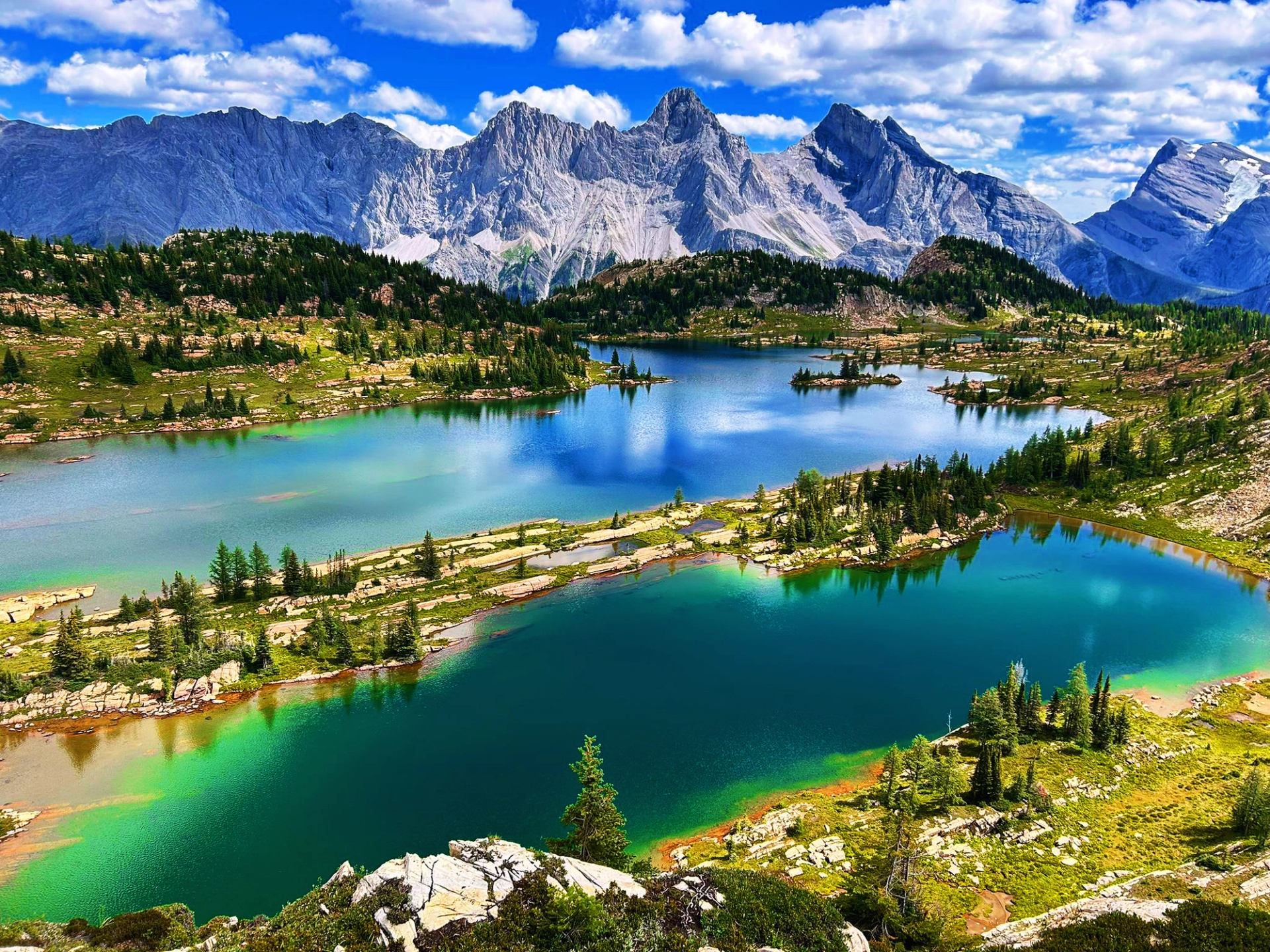 Vibrant lakes surrounded by jagged mountain peaks under blue sky
