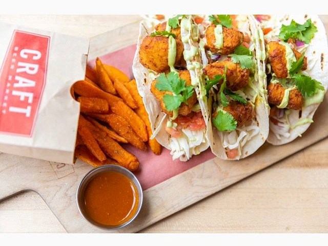 Tacos with crispy toppings, sweet potato fries, and sauce at CRAFT Beer Market.