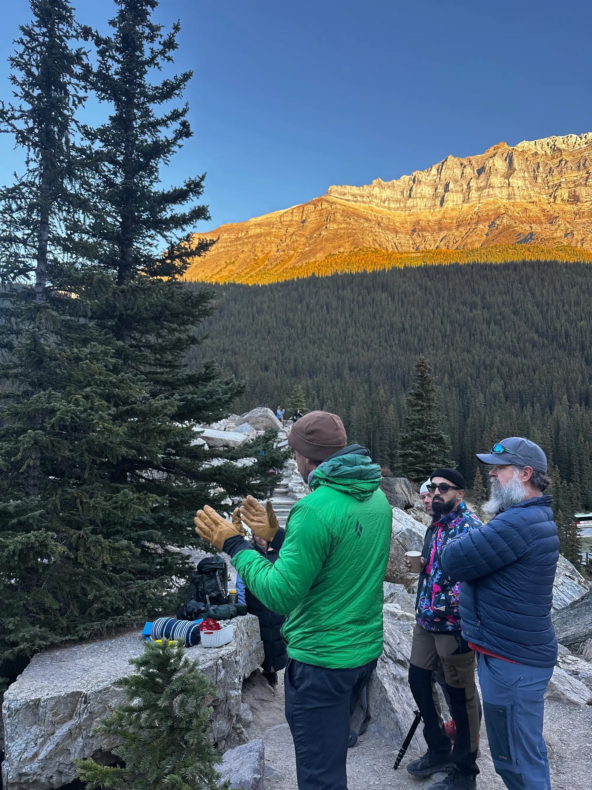 Hikers pause in sunlit mountains for a photography moment.