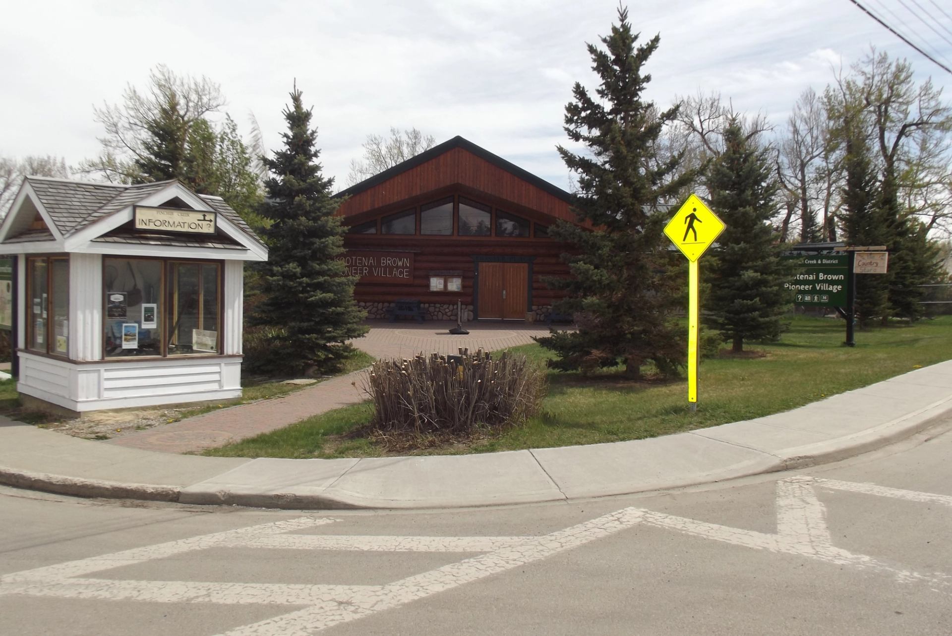 Visitor info signs and rustic buildings at Pincher Creek VIC near crosswalk.
