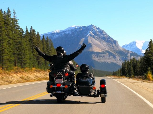 Motorcycle tour through trees and mountains in Jasper.