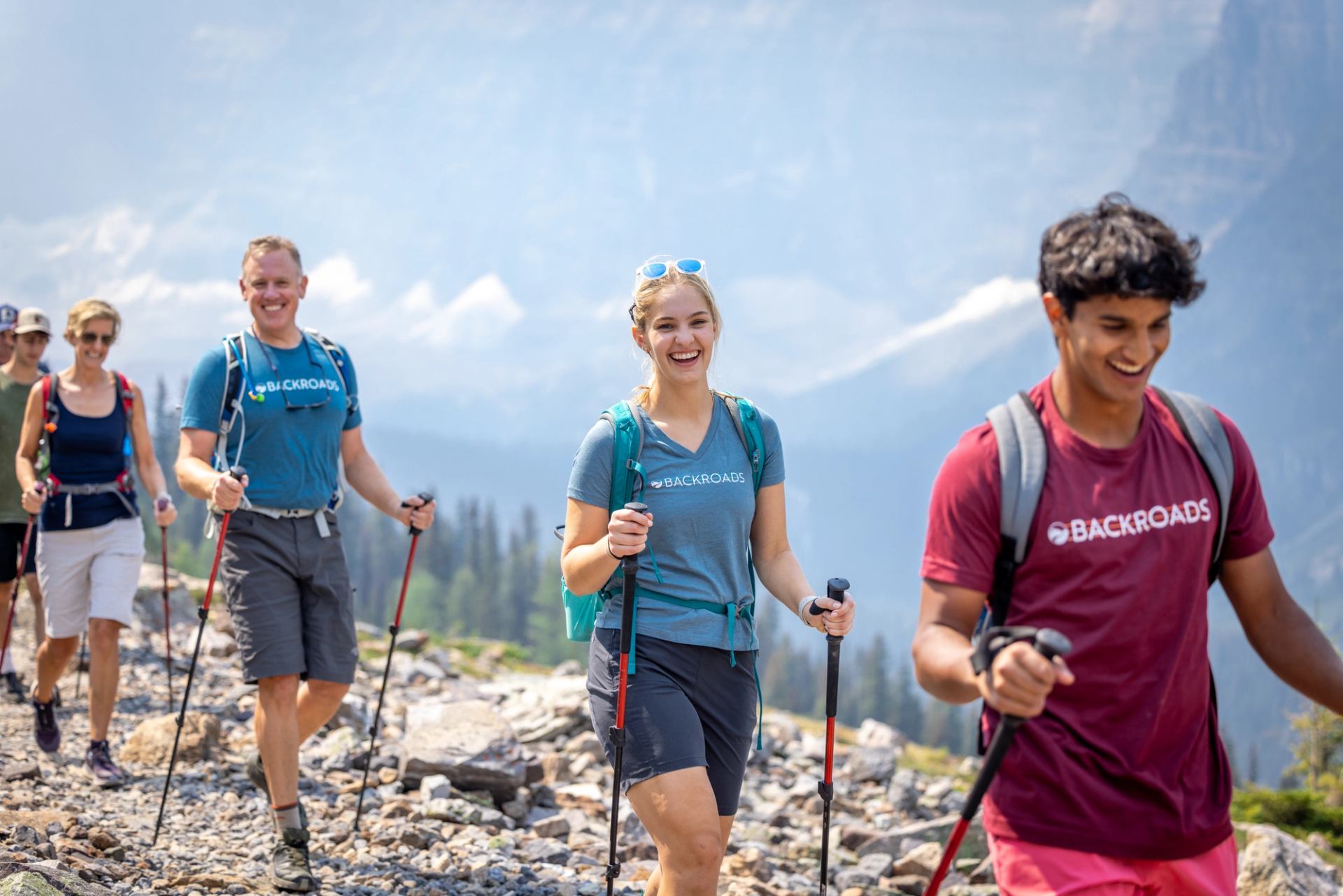 Hikers on a rocky mountain trail with scenic peaks in the background.