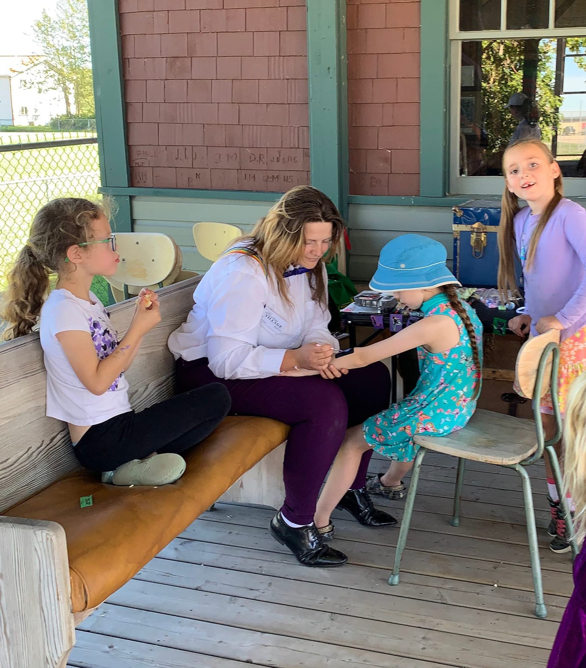 Adult and child seated outdoors during craft or tattoo activity.
