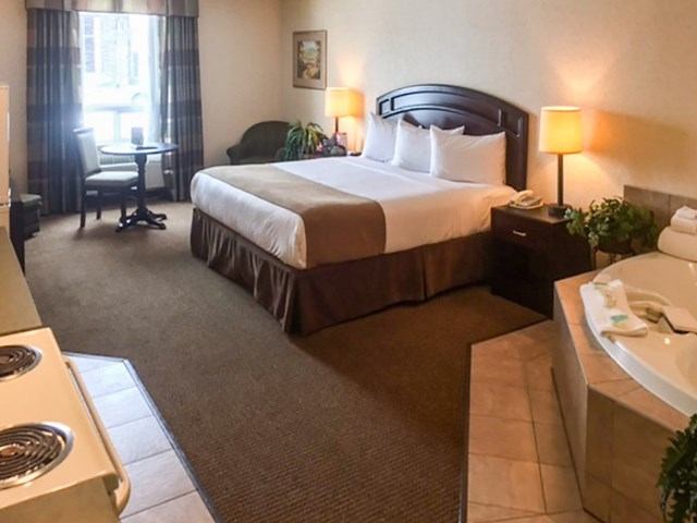 Hotel room with bed, desk, armchair, and in-room jacuzzi tub.