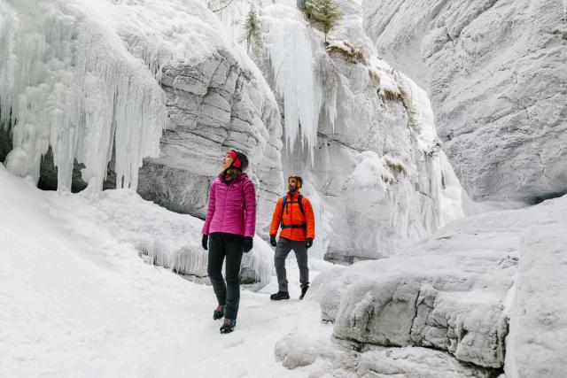 People looking up at the frozen waterfalls in Maligne Canyon.