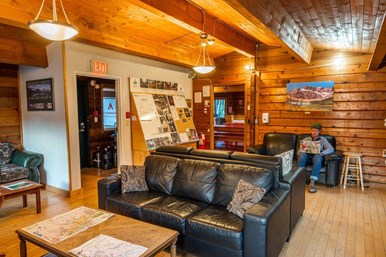 Common room at HI Kananaskis with leather sofas, wooden walls and ceilings, community bulletin board.