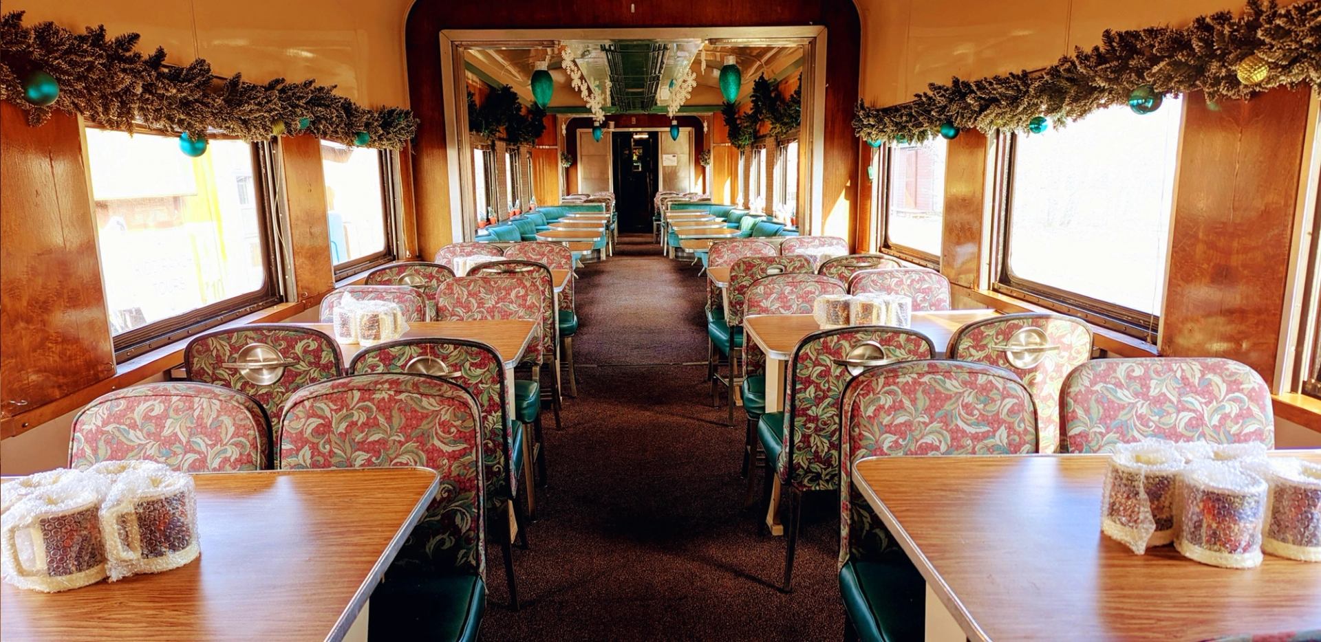 Vintage dining car with patterned seats, wooden tables and festive garlands.