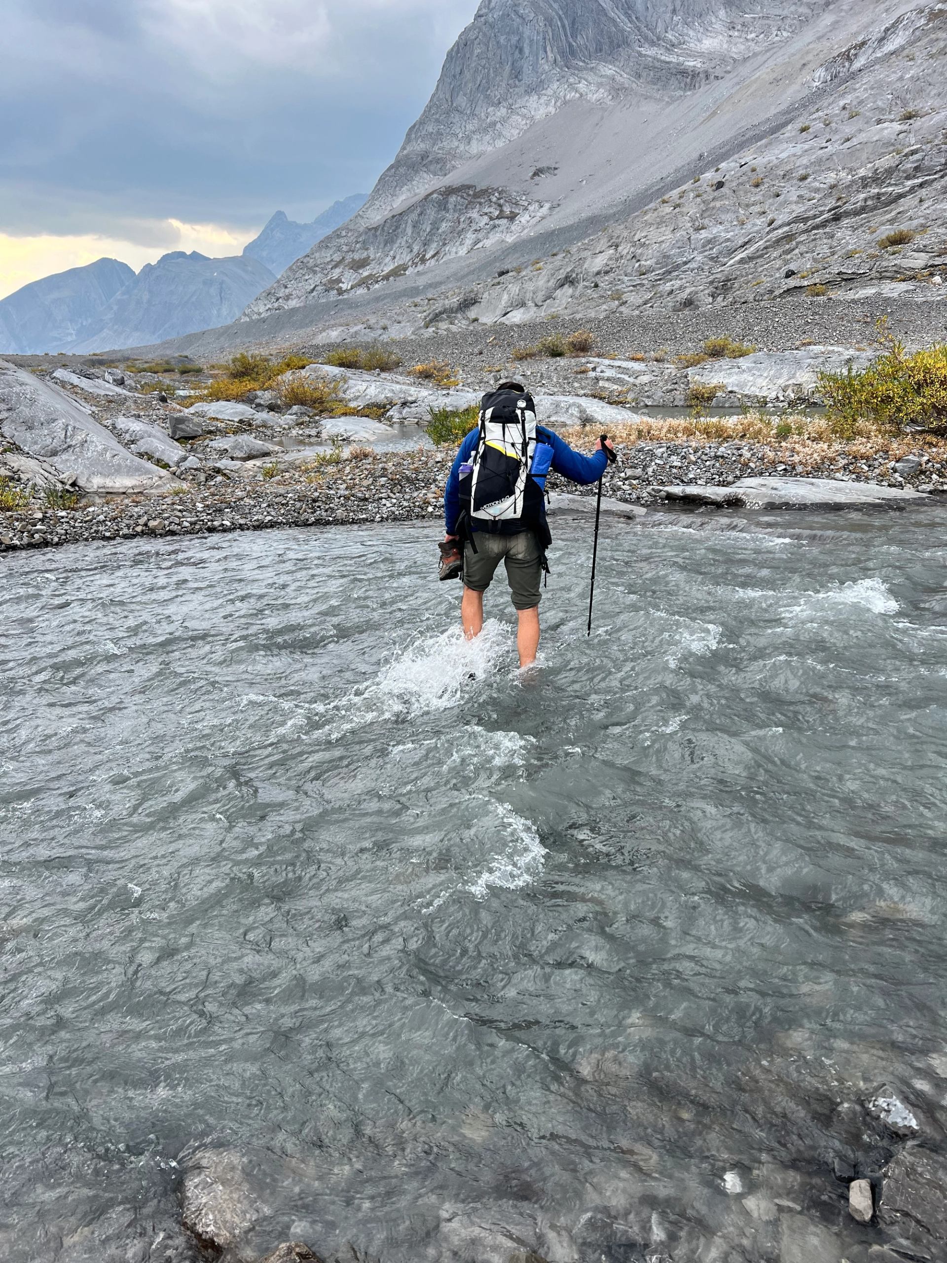 Hiker wades through rocky stream in Canadian Rockies