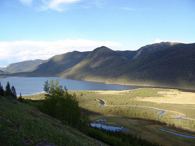 Mountain valley with winding rivers, forests, and patches of autumn color.