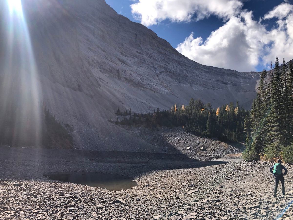 A small rocky basin with a shallow pool beneath massive cirque walls and trees.