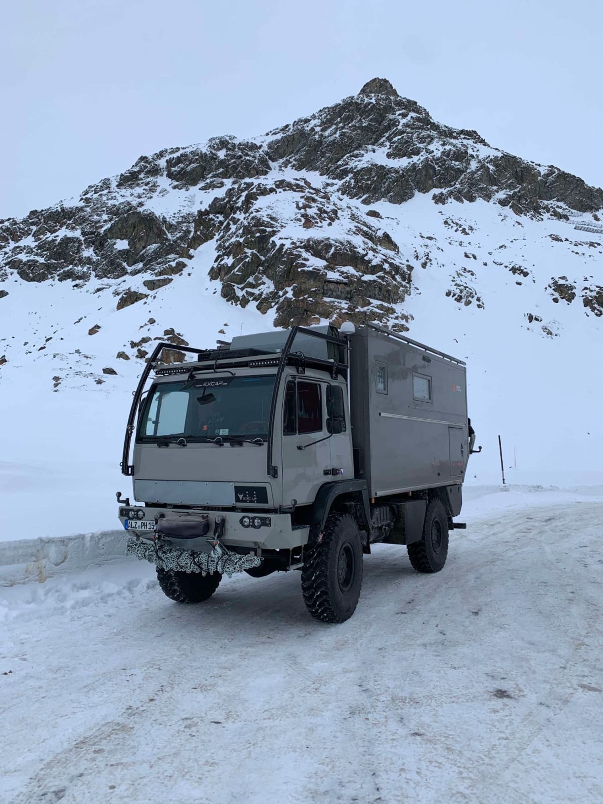 Rugged off-road truck on snowy road with mountain backdrop, built for extreme terrain.