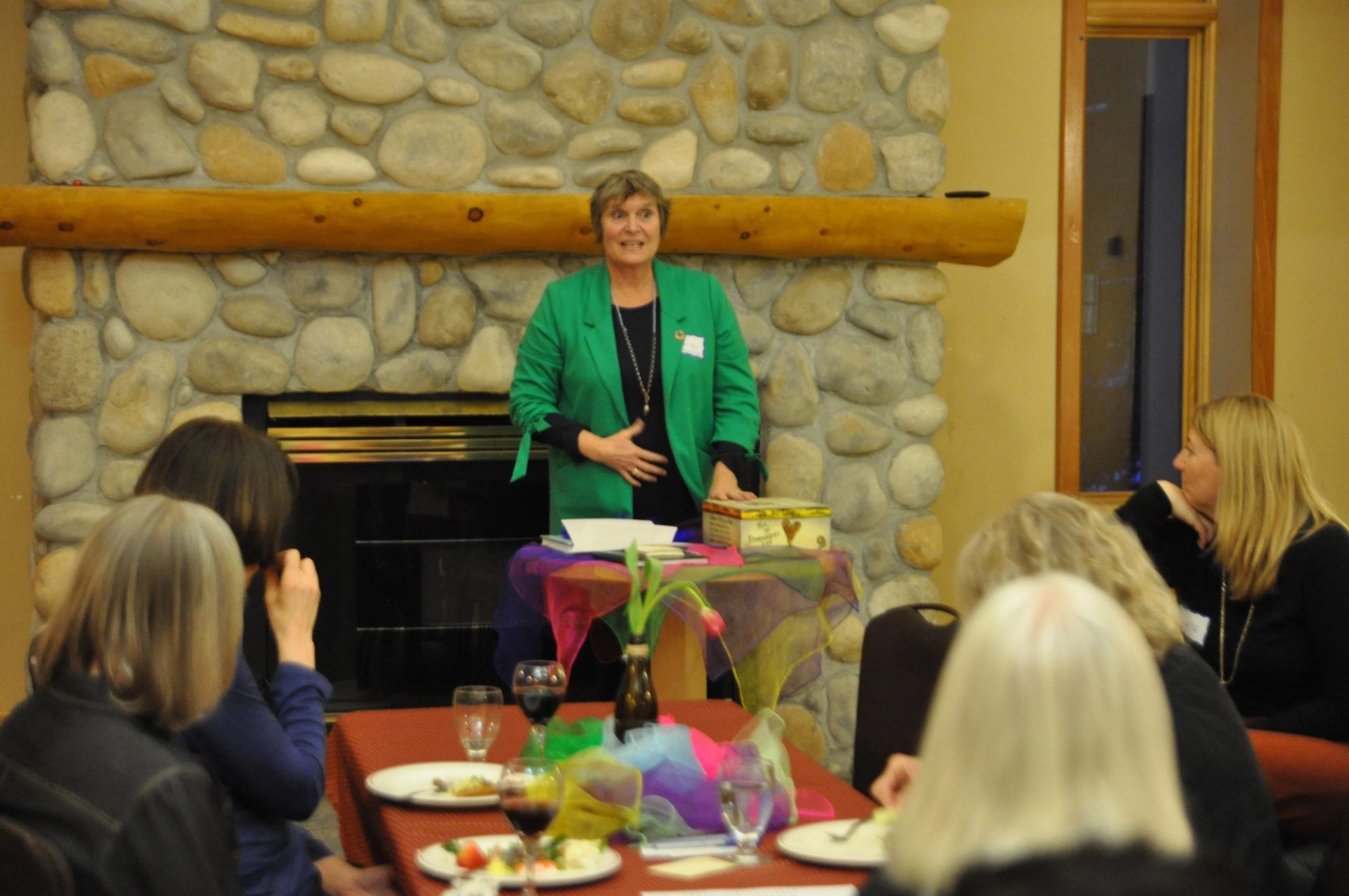 Woman in green jacket speaking to a group of women