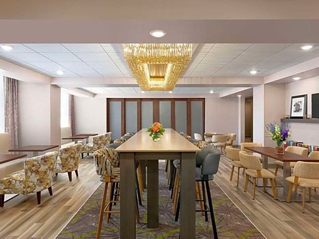 Conference room at The Landing with high table, bar stools, armchairs, and chandelier lighting.