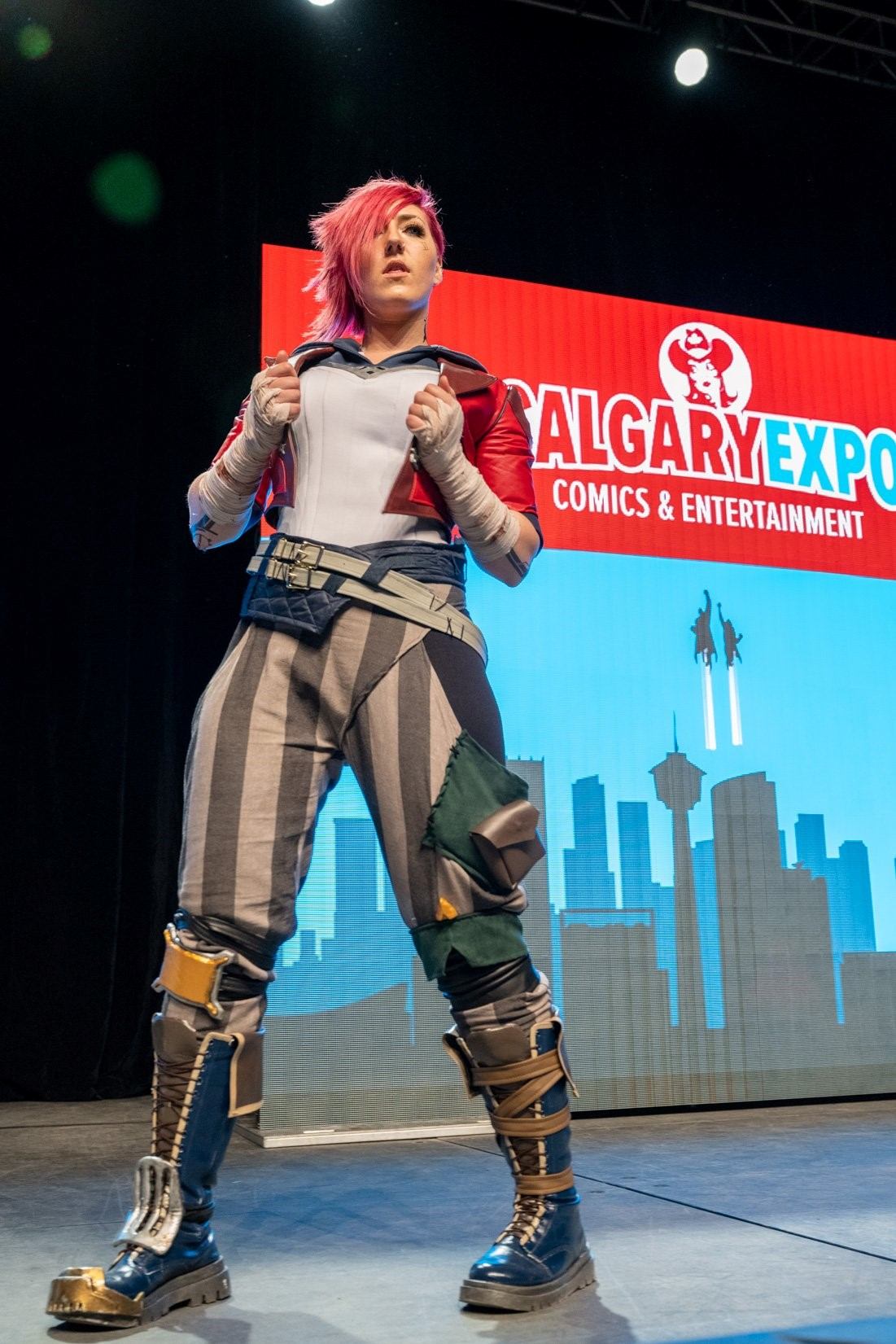 Cosplayer in a detailed red, white, and blue outfit striking a strong pose on stage at the Calgary Expo.