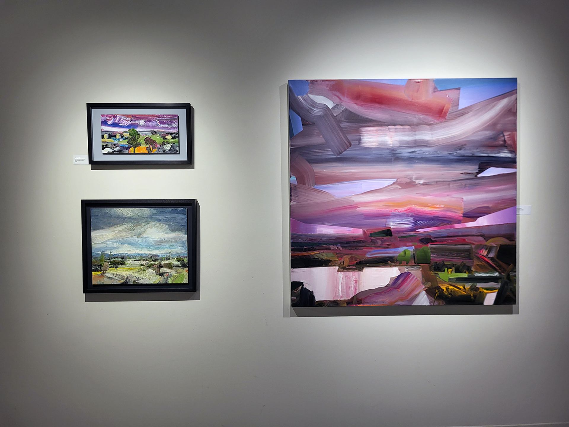 Three colorful landscape paintings displayed on a gallery wall at Wallace Galleries.