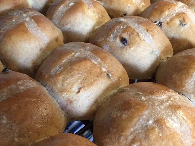 Pile of small round pastries with sugar and raisin filling on display.