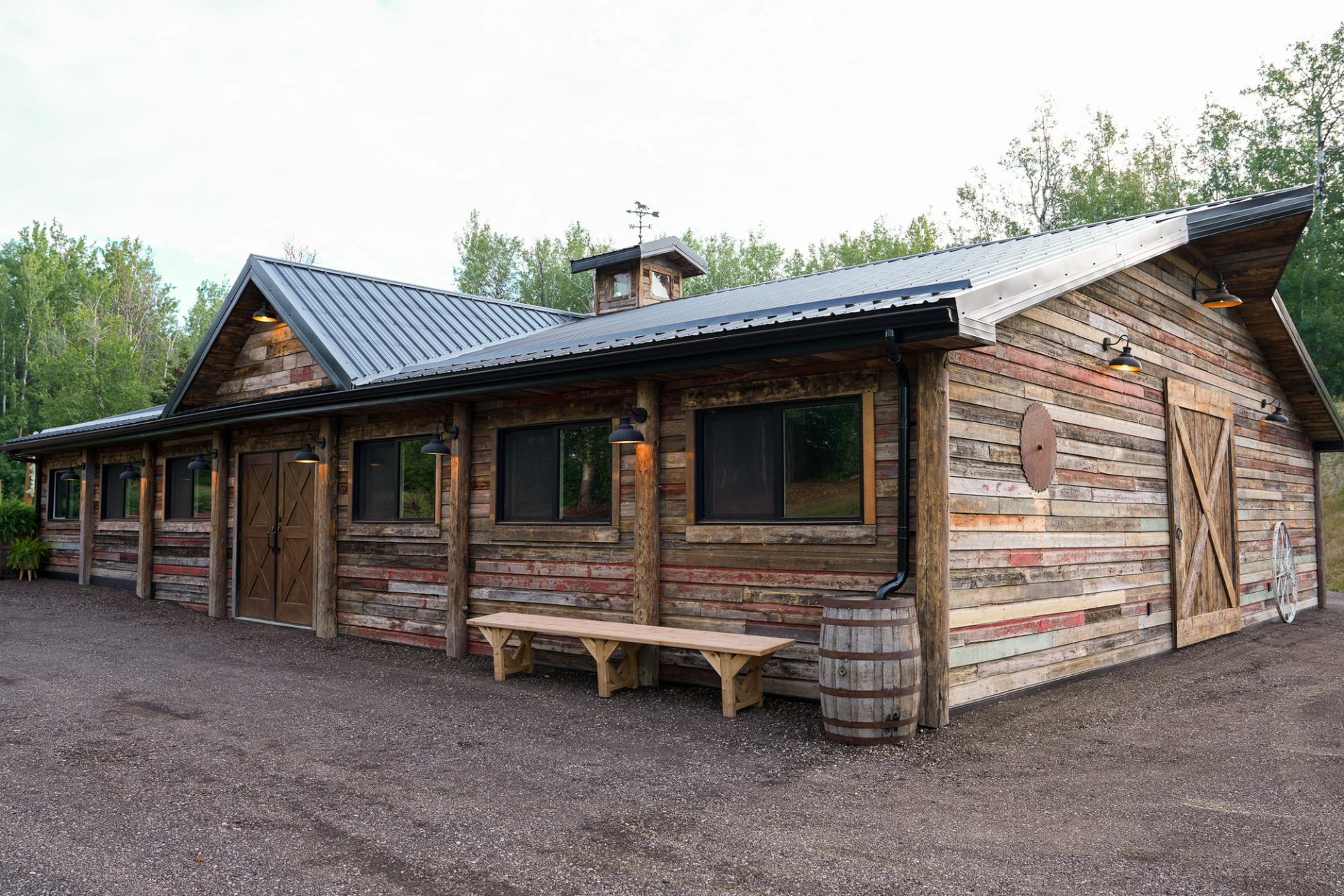 Rustic wooden building with metal roof, surrounded by trees and outdoor decor.