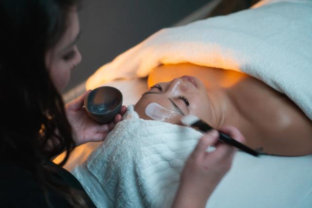 Massage thereapist applying facial mask.