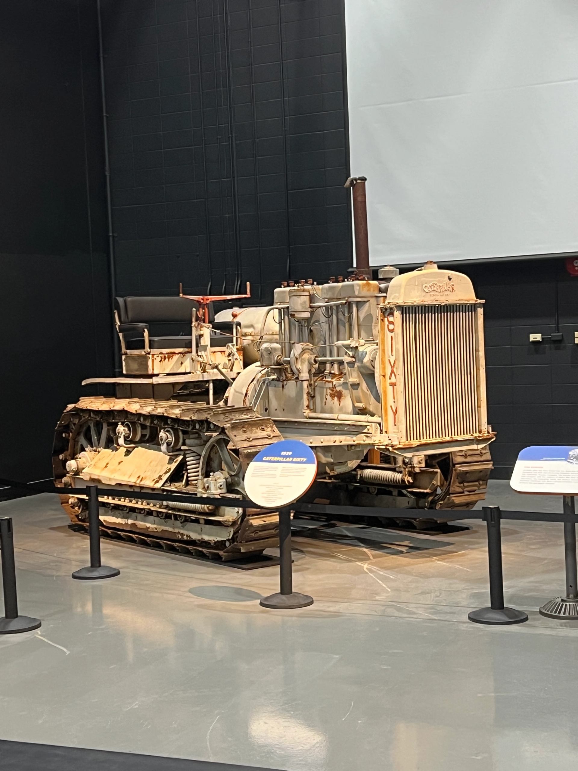 Snowmobile displayed in an indoor museum exhibit with stanchions and information placards.