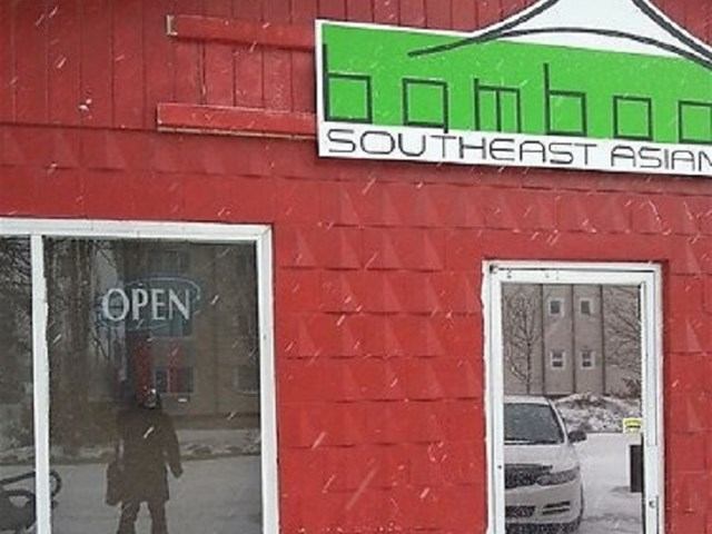 Exterior of Bamboo Southeast Asian restaurant with snow and an "OPEN" sign.