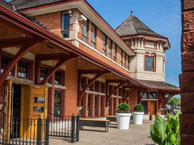 Historic brick and stone building with tower, planters, and wooden beams.