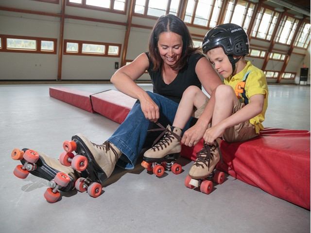 Mother helping her son tie up his rollarskates.