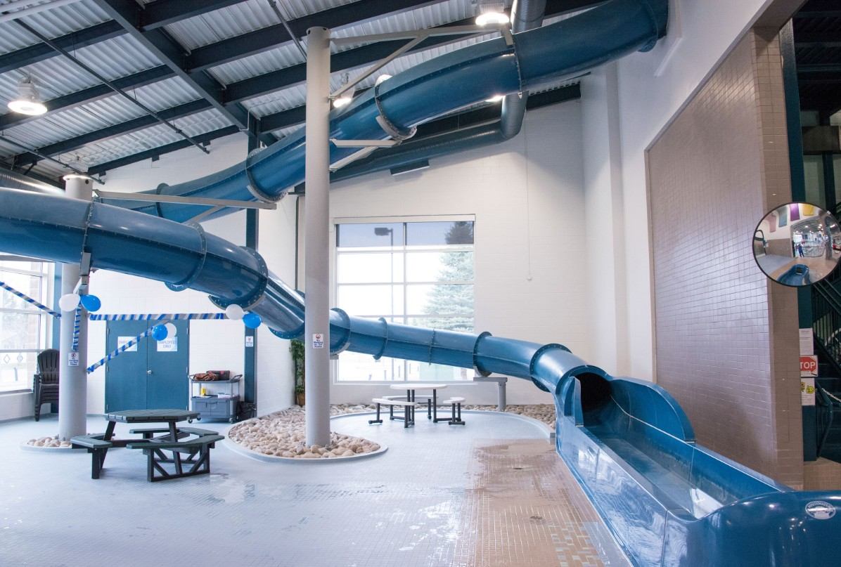 Large twisting blue waterslide ending in splash zone inside aquatic centre