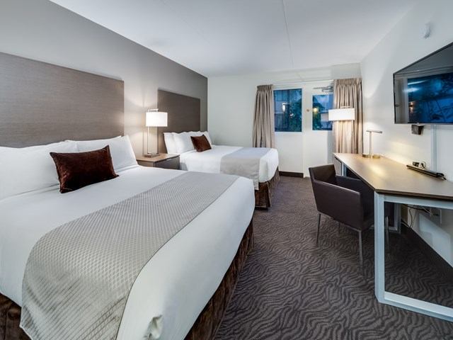 Modern hotel room with two queen beds, desk, and flat-screen TV at Heritage Inn.